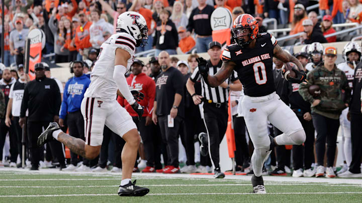 Oklahoma State's Ollie Gordon II runs the ball against Texas Tech's C.J. Baskerville during an NCAA football game on Saturday, Nov. 23, 2024, in Stillwater, Okla.