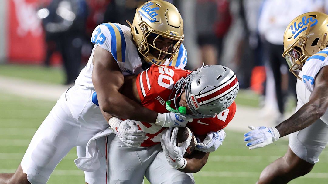 Nov 15, 2025; Columbus, Ohio, USA; Ohio State Buckeyes running back James Peoples (20) runs the ball as UCLA Bruins linebacker Isaiah Chisom (32) makes the tackle during the fourth quarter at Ohio Stadium. Mandatory Credit: Joseph Maiorana-Imagn Images