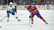 Jan 6, 2025; Montreal, Quebec, CAN; Montreal Canadiens defenseman Lane Hutson (48) plays the puck and Vancouver Canucks forward Kiefer Sherwood (44) defends during the second period at the Bell Centre. Mandatory Credit: Eric Bolte-Imagn Images
