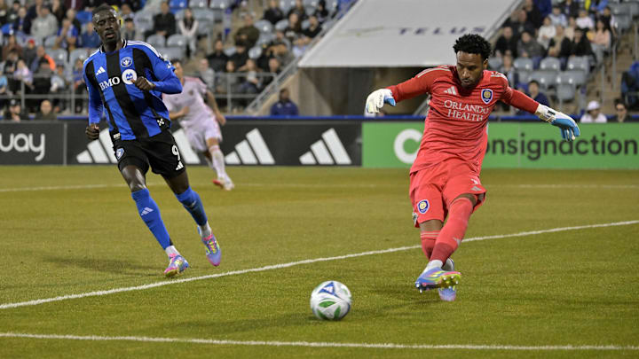 Apr 19, 2025; Montreal, Province of Quebec, CAN; Orlando City goalkeeper Pedro Gallese (1) kicks the ball next to CF Montreal forward Prince Owusu (9) during the first half at Saputo Stadium. Mandatory Credit: Eric Bolte-Imagn Images