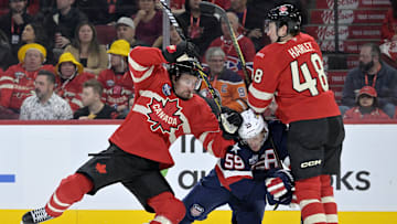 Feb 15, 2025; Montreal, Quebec, CAN; [Imagn Images direct customers only] Team Canada forward Mark Stone (61) and teammate Team Canada defenseman Thomas Harley (48) check Team United States forward Jake Guentzel (59) in the third period during a 4 Nations Face-Off ice hockey game at the Bell Centre. Mandatory Credit: Eric Bolte-Imagn Images