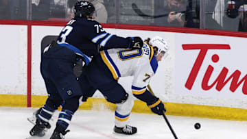 Apr 21, 2025; Winnipeg, Manitoba, CAN; Winnipeg Jets left wing Brandon Tanev (73) checks St. Louis Blues center Oskar Sundqvist (70) in the third period in game two of the first round of the 2025 Stanley Cup Playoffs at Canada Life Centre. Mandatory Credit: James Carey Lauder-Imagn Images