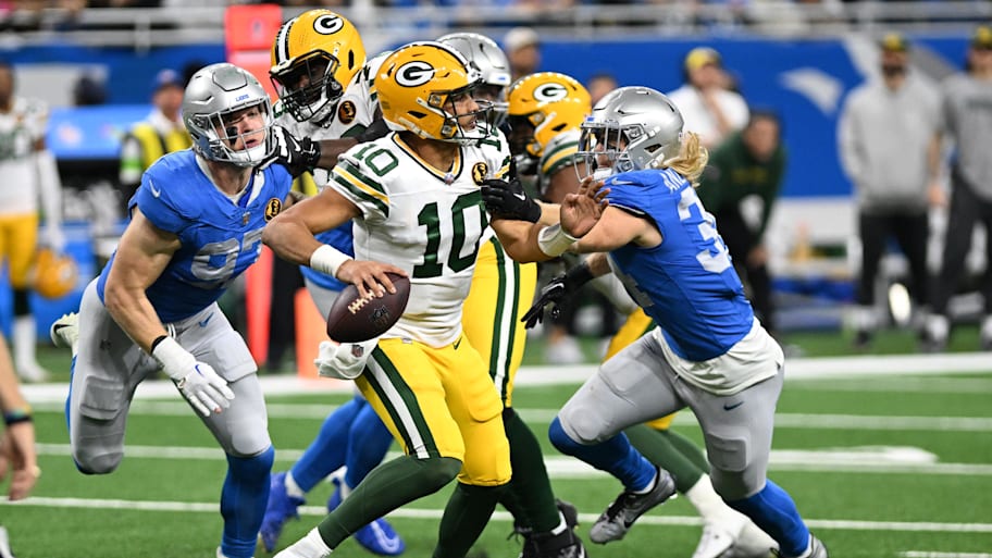 Green Bay Packers quarterback Jordan Love (10) looks to throw a pass as Lions pass rushers close in.