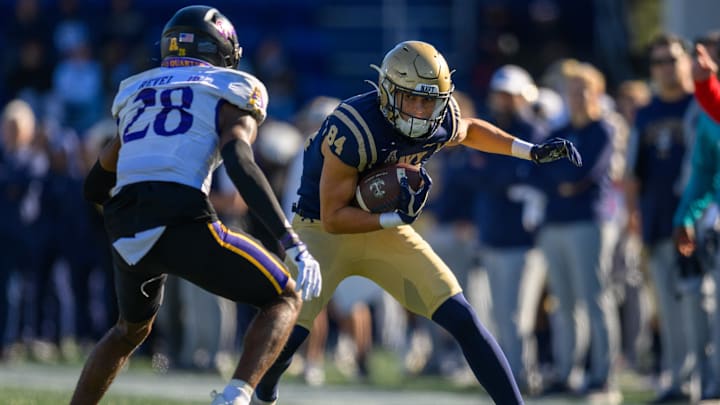 Nov 18, 2023; Annapolis, Maryland, USA; Navy Midshipmen wide receiver Regis Velez (84) runs the ball against East Carolina Pirates defensive back Shavon Revel (28) during the second quarter at Navy-Marine Corps Memorial Stadium. Mandatory Credit: Reggie Hildred-Imagn Images
