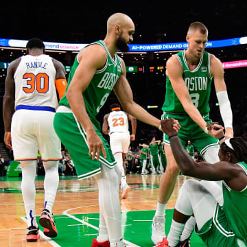 Dec 8, 2023; Boston, Massachusetts, USA;  Boston Celtics guard Jrue Holiday (4) is helped to his feet by guard Derrick White (9)  and center Kristaps Porzingis (8) during the first half against the New York Knicks at TD Garden. Mandatory Credit: Eric Canha-USA TODAY Sports