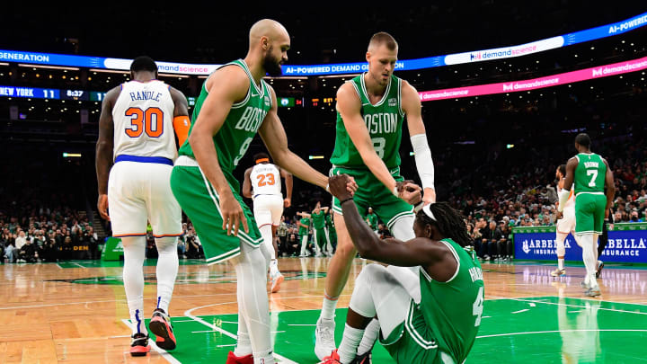 Dec 8, 2023; Boston, Massachusetts, USA;  Boston Celtics guard Jrue Holiday (4) is helped to his feet by guard Derrick White (9)  and center Kristaps Porzingis (8) during the first half against the New York Knicks at TD Garden. Mandatory Credit: Eric Canha-USA TODAY Sports