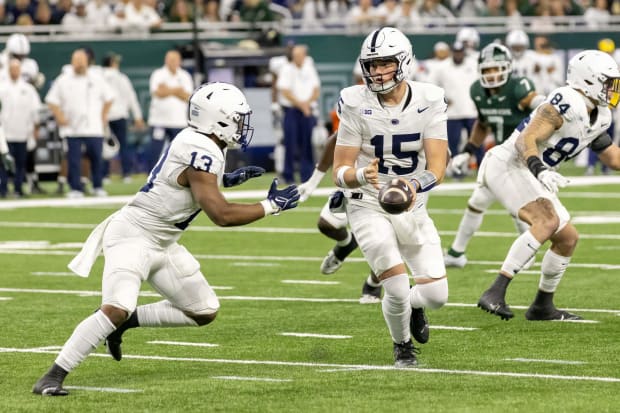 Penn State quarterback Drew Allar hands the ball to running back Kaytron Allen during a football game.