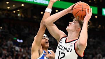 Nov 15, 2025; Boston, Massachusetts, USA; UConn Huskies center Eric Reibe (12) shoots against the defense of BYU Cougars center Xavion Staton (33) during the first half at TD Garden.