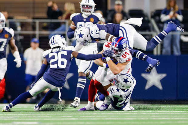 New York Giants TE Theo Johnson is tackled by Dallas Cowboys S Israel Mukuamu, LB DeMarvion Overshown, and CB DaRon Bland.