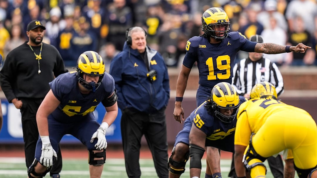 Michigan head coach Sherrone Moore, left, and associate head coach Biff Poggi watch quarterback Bryce Underwood (19) 