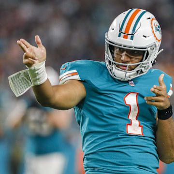 Jan 9, 2022; Miami Gardens, Florida, USA; Miami Dolphins quarterback Tua Tagovailoa (1) reacts with wide receiver Jaylen Waddle (17) after running with the football for a first down against the New England Patriots during the fourth quarter at Hard Rock Stadium. 