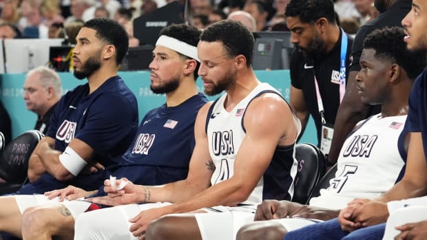 Team USA's Jayson Tatum, Devin Booker, Stephen Curry, and Anthony Edwards look on from the bench during a game vs. Serbia.