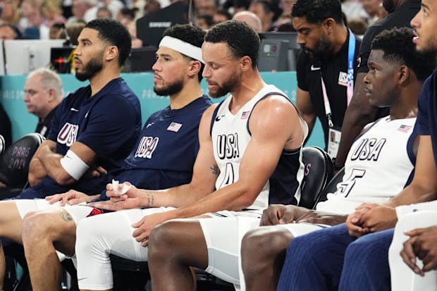 Team USA's Jayson Tatum, Devin Booker, Stephen Curry, and Anthony Edwards look on from the bench during a game vs. Serbia.