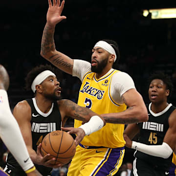 Apr 12, 2024; Memphis, Tennessee, USA; Memphis Grizzlies guard Jordan Goodwin (4) drives to the basket between Los Angeles Lakers forward LeBron James (23) and forward Anthony Davis (3) during the second half at FedExForum. 