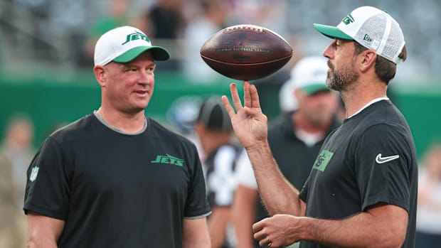 New York Jets quarterback Aaron Rodgers (right) spins the ball in front of offensive coordinator Nathaniel Hackett (left).