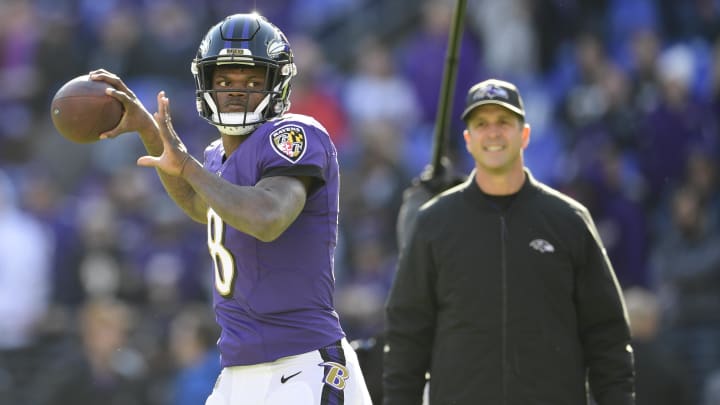 Jan 6, 2019; Baltimore, MD, USA; Baltimore Ravens quarterback Lamar Jackson (8) passes as head coach John Harbaugh looks prior to the game against the Los Angeles Chargers in a AFC Wild Card playoff football game at M&T Bank Stadium. 