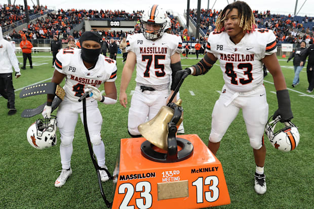 Massillon players Shon Robinson, left, Michael Looney and Malachi Card ring the victory bell after beating McKinley in 2023.