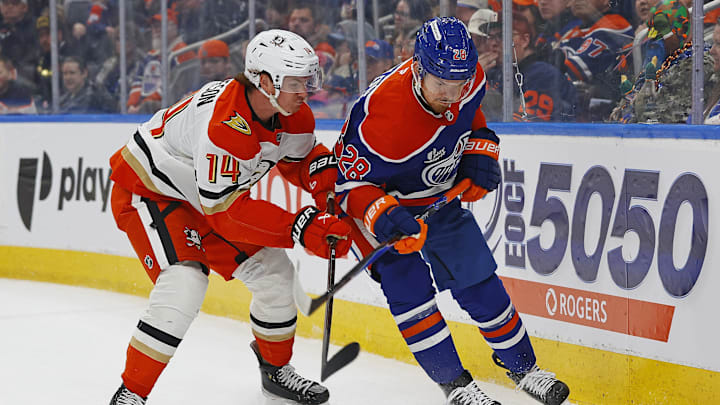 Mar 28, 2026; Edmonton, Alberta, CAN; Anaheim Ducks defensemen Drew Helleson (14) and Edmonton Oilers forward Jack Roslovic (28) battle for a loose puck during the first period at Rogers Place. Mandatory Credit: Perry Nelson-Imagn Images