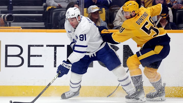 Mar 22, 2025; Nashville, Tennessee, USA; Toronto Maple Leafs center John Tavares (91) moves the puck past Nashville Predators defenseman Roman Josi (59) during the first period of their game at Bridgestone Arena. Mandatory Credit: Alan Poizner-Imagn Images
