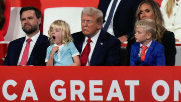 Carolina Trump, daughter of Eric Trump, yawns while sitting on the lap of Donald Trump while Eric Trump speaks during the final day of the Republican National Convention at the Fiserv Forum. At left is JD Vance, at right is Lara Trump and Luke Trump. The final day of the RNC featured a keynote address by Republican presidential nominee Donald Trump.