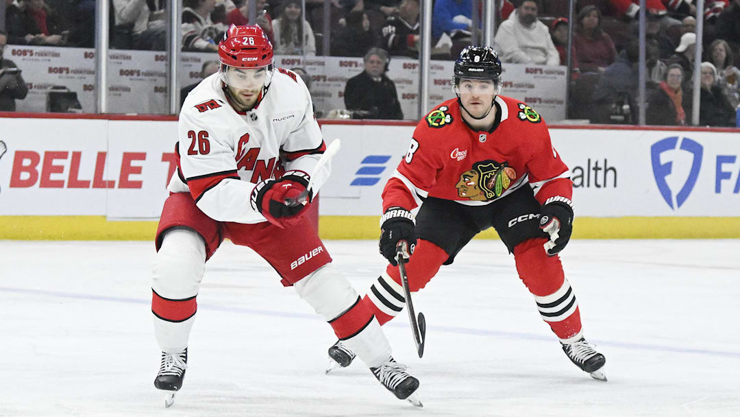 Jan 20, 2025; Chicago, Illinois, USA;  Carolina Hurricanes defenseman Sean Walker (26) moves the puck against Chicago Blackhawks center Ryan Donato (8) during the first period at the United Center. Mandatory Credit: Matt Marton-Imagn Images


