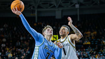 Feb 23, 2025; Wichita, Kansas, USA; Tulane Green Wave guard Rowan Brumbaugh (7) shoots the ball around Wichita State Shockers guard Xavier Bell (1) during the first half at Charles Koch Arena. 