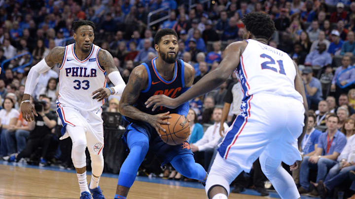 Jan 28, 2018; Oklahoma City, OK, USA; Oklahoma City Thunder forward Paul George (13) drives to the basket between Philadelphia 76ers forward Robert Covington (33) and center Joel Embiid (21) during the fourth quarter at Chesapeake Energy Arena. Mandatory Credit: Mark D. Smith-Imagn Images