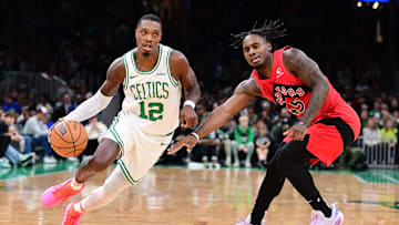 Oct 13, 2024; Boston, Massachusetts, USA; Boston Celtics guard Lonnie Walker IV (12) controls the ball while Toronto Raptors guard Davion Mitchell (45) defends during the first half at TD Garden. Mandatory Credit: Bob DeChiara-Imagn Images