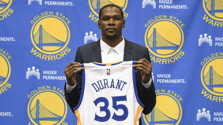Kevin Durant poses for a photo with his jersey during a press conference after signing with the Golden State Warriors.