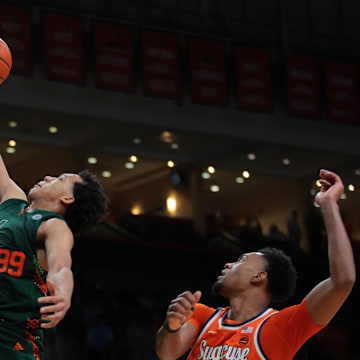 Feb 11, 2025; Coral Gables, Florida, USA; Miami Hurricanes guard Divine Ugochukwu (99) drives to the basket past Syracuse Orange guard J.J. Starling (2) during the second half at Watsco Center. Mandatory Credit: Sam Navarro-Imagn Images