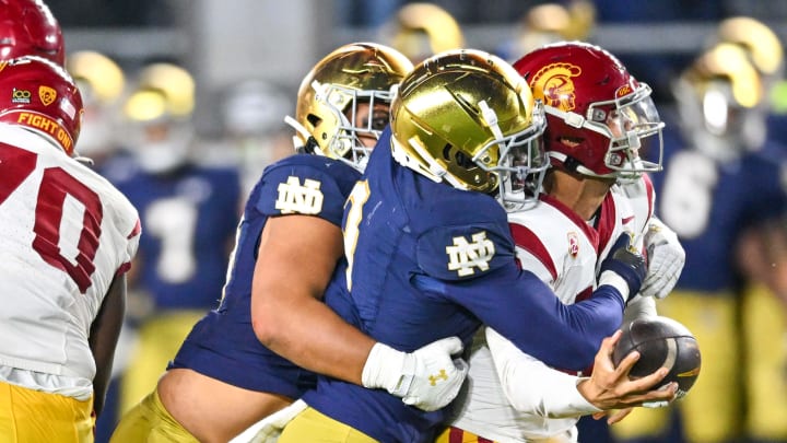 Oct 14, 2023; South Bend, Indiana, USA; USC Trojans quarterback Caleb Williams (13) is tackled by Notre Dame Fighting Irish linebacker Jaylen Sneed (3) and defensive lineman Howard Cross III (56) in the fourth quarter at Notre Dame Stadium. Notre Dame won 48-20