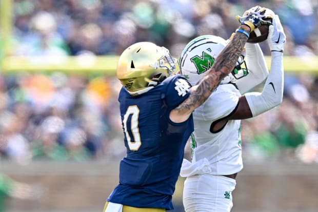 Football player Micah Abraham intercepts a pass in a white jersey.