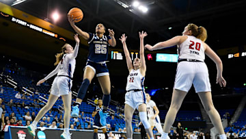 Mar 21, 2025; Los Angeles, California, USA; Richmond Spiders guard Katie Hill (25) drives to the basket between Richmond Spiders forward Maggie Doogan (44) and Richmond Spiders guard Rachel Ullstrom (22) during the first quarter of an NCAA Tournament first-round game at Pauley Pavilion presented by Wescom. Mandatory Credit: Robert Hanashiro-Imagn Images
