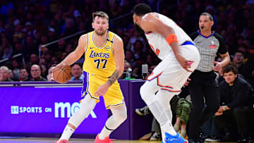 Mar 6, 2025; Los Angeles, California, USA; Los Angeles Lakers guard Luka Doncic (77) moves the ball against New York Knicks center Karl-Anthony Towns (32) during the second half at Crypto.com Arena. Mandatory Credit: Gary A. Vasquez-Imagn Images