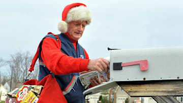 A mail carrier during Christmastime dressed up in festive gear
