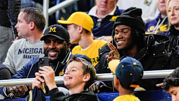 Michigan football head coach Sherrone Moore, left, and quarterback signee Bryce Underwood take selfies with fans at halftime of the basketball game between Michigan and Iowa at Crisler Center in Ann Arbor on Saturday, Dec. 7, 2024.