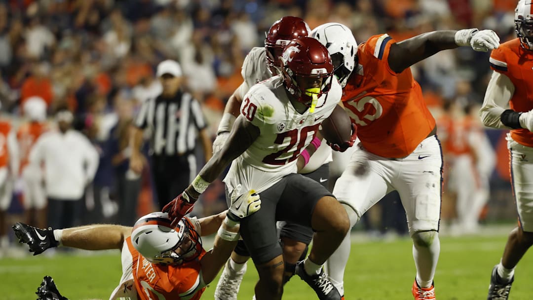 Oct 18, 2025; Charlottesville, Virginia, USA; Washington State Cougars running back Leo Pulalasi (20) carries the ball as Virginia Cavaliers safety Ethan Minter (30) attempts a tackle during the first half at Scott Stadium. Mandatory Credit: Geoff Burke-Imagn Images