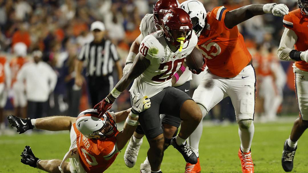 Oct 18, 2025; Charlottesville, Virginia, USA; Washington State Cougars running back Leo Pulalasi (20) carries the ball as Virginia Cavaliers safety Ethan Minter (30) attempts a tackle during the first half at Scott Stadium. Mandatory Credit: Geoff Burke-Imagn Images