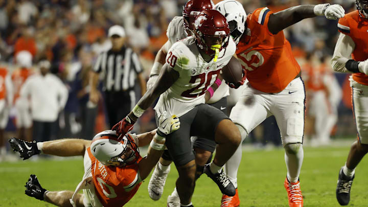 Oct 18, 2025; Charlottesville, Virginia, USA; Washington State Cougars running back Leo Pulalasi (20) carries the ball as Virginia Cavaliers safety Ethan Minter (30) attempts a tackle during the first half at Scott Stadium. Mandatory Credit: Geoff Burke-Imagn Images