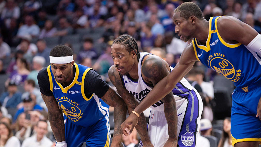 Oct 9, 2024; Sacramento, California, USA; Golden State Warriors guard Gary Payton II (0) and forward Jonathan Kuminga (00) defend against Sacramento Kings forward DeMar DeRozan (10) during a free throw attempt in the second quarter at Golden 1 Center. Mandatory Credit: Ed Szczepanski-Imagn Images
