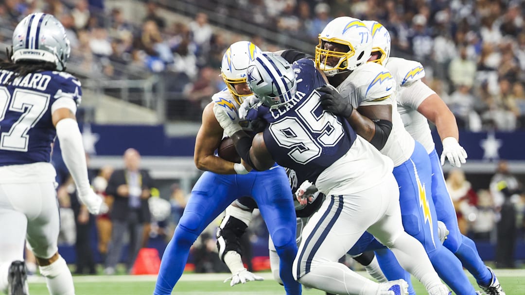 Dec 21, 2025; Arlington, Texas, USA; Dallas Cowboys defensive tackle Kenny Clark (95) tackles Los Angeles Chargers quarterback Justin Herbert (10) for a short gain during the third quarter at AT&T Stadium. Los Angeles Chargers guard Zion Johnson (77) blocks against Clark at right. Mandatory Credit: Kevin Jairaj-Imagn Images