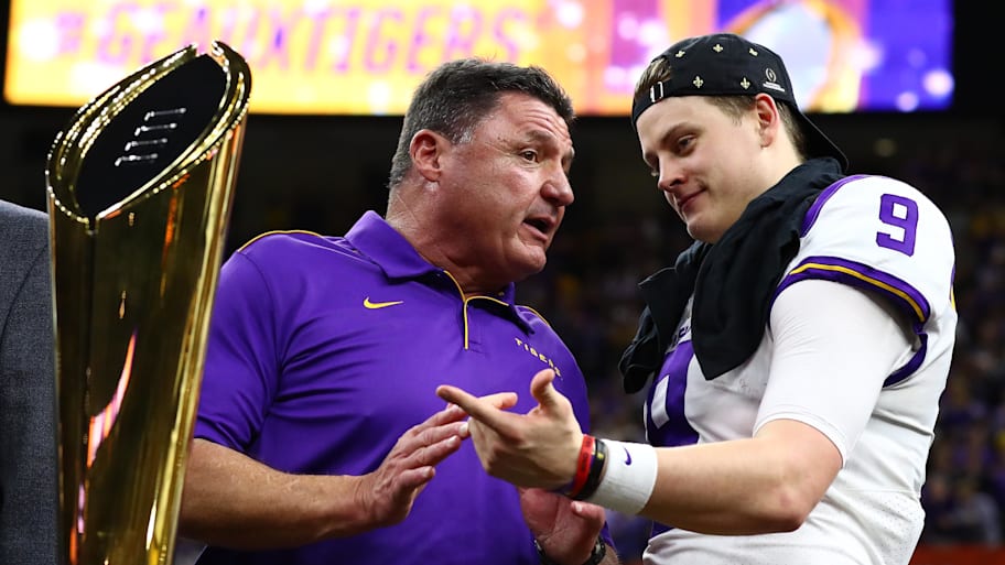 Jan 13, 2020; New Orleans, Louisiana, USA; LSU Tigers head coach Ed Orgeron talks with quarterback Joe Burrow as Joe points to the national championship trophy after a victory against the Clemson Tigers in the College Football Playoff national championship game at Mercedes-Benz Superdome. Mandatory Credit: Matthew Emmons-Imagn Images | Matthew Emmons-Imagn Images