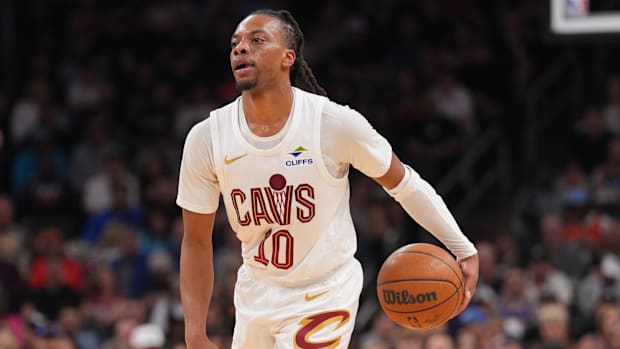 A basketball player dribbling a basketball while wearing a white uniform.