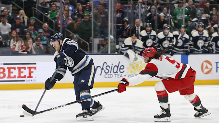 Mar 17, 2026; Columbus, Ohio, USA; Columbus Blue Jackets center Mathieu Olivier (24) wrists a shot on goal as Carolina Hurricanes defenseman Jalen Chatfield (5) defends during the second period at Nationwide Arena. Mandatory Credit: Russell LaBounty-Imagn Images