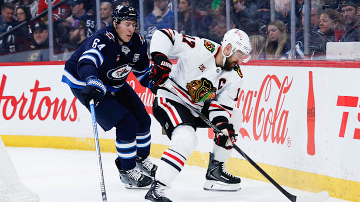 Mar 3, 2026; Winnipeg, Manitoba, CAN;  Chicago Blackhawks forward Nick Foligno (17) shields the puck from Winnipeg Jets defenseman Logan Stanley (64) during the first period at Canada Life Centre. Mandatory Credit: Terrence Lee-Imagn Images