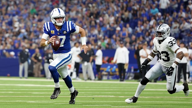 Colts quarterback Daniel Jones (blue and white uniform) runs away from a defender in pursuit.