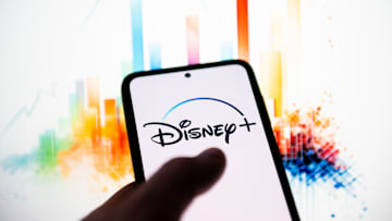 In this photo illustration a Disney + logo seen displayed on...