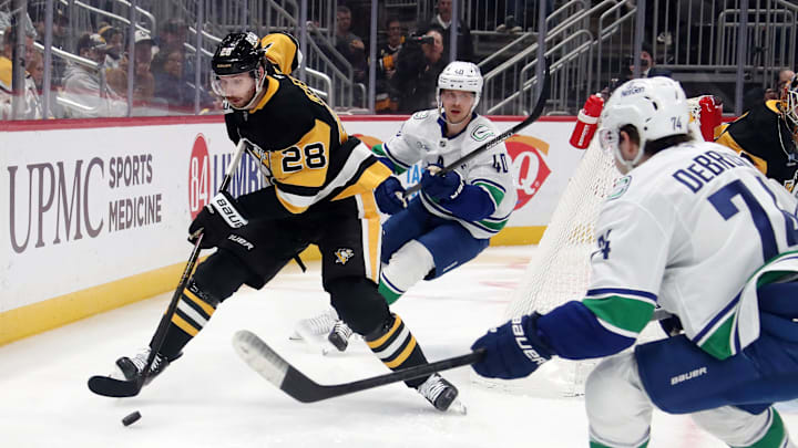 Nov 27, 2024; Pittsburgh, Pennsylvania, USA;  Pittsburgh Penguins defenseman Marcus Pettersson (28) moves the puck against Vancouver Canucks center Elias Pettersson (40) and Vancouver Canucks left wing Jake DeBrusk (74) during the second period at PPG Paints Arena. Mandatory Credit: Charles LeClaire-Imagn Images