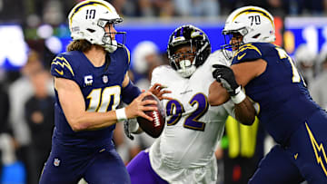 Nov 26, 2023; Inglewood, California, USA; Los Angeles Chargers quarterback Justin Herbert (10) moves out to pass as offensive tackle Rashawn Slater (70) provides coverage against Baltimore Ravens defensive tackle Justin Madubuike (92) during the first half at SoFi Stadium. Mandatory Credit: Gary A. Vasquez-Imagn Images
