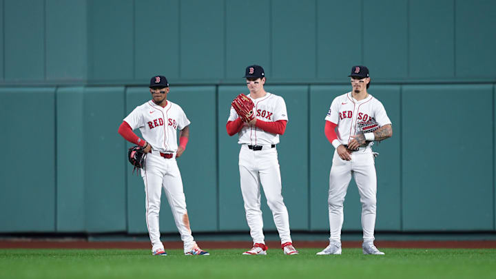 Boston Red Sox outfielders Ceddanne Rafaela, Jarren Duran, and Roman Anthony watch a pitching change in Fenway Park.